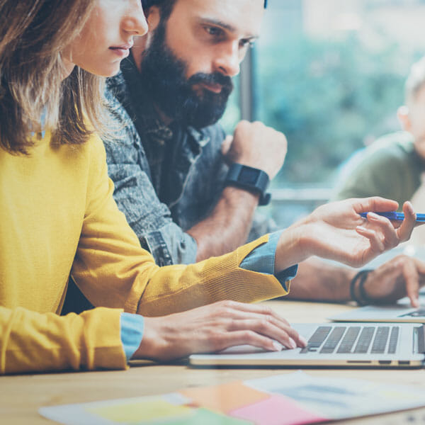 Menschen an einem Schreibtisch mit Laptops, die über die Erstellung von APIs diskutieren.